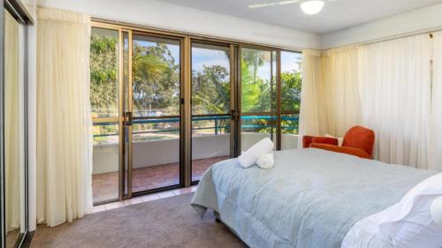 a bedroom with a bed and a large window at Placid Waters Holiday Apartments in Bongaree
