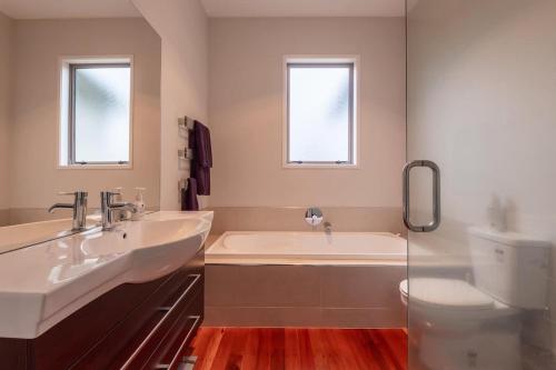 a bathroom with two sinks and a tub and a toilet at Lake View Inn in Rotorua