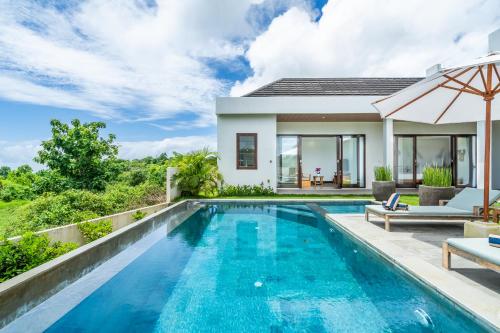 a villa with a swimming pool and a house at Akasia Hill Villas in Nusa Dua