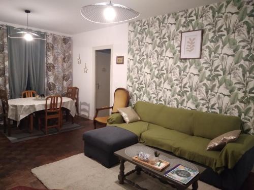 un salon avec un canapé vert et une table dans l'établissement Maison de village proche du Lac de Vassivière, à Peyrat-le-Château