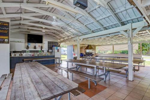 a cafeteria with wooden picnic tables and a kitchen at Kurrimine Beach Holiday Park in Kurrimine Beach
