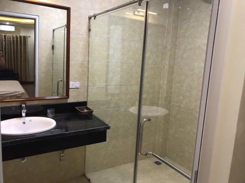 Un baño con lavabo y ducha de cristal. en Hòa Bình Hotel LC - by BAY LUXURY, en Cốc Lếu