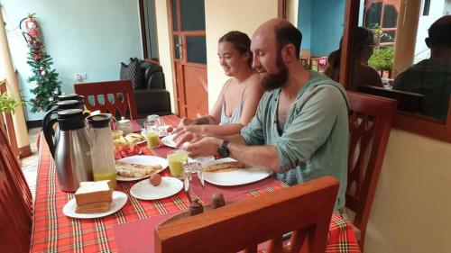 a man and woman sitting at a table with food at Kisanga Homestay in Moshi