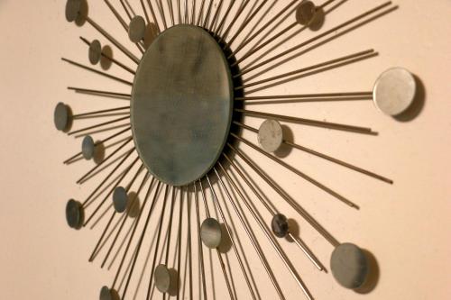 a large metal sunburst clock on a wall at ホテル宿かいふ in Kaiyo