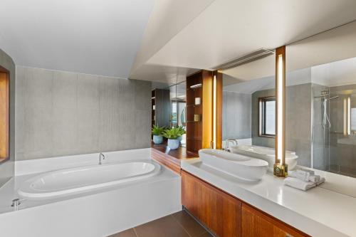 a bathroom with two sinks and a tub and a mirror at Yacht Club Villas on Hamilton Island by HIHA in Hamilton Island