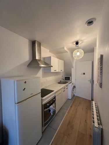 Il comprend une cuisine équipée d'un réfrigérateur blanc et d'une cuisinière. dans l'établissement Petit refuge, à Saint-Brieuc