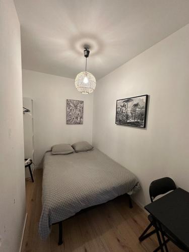 - une petite chambre avec un lit et un lustre dans l'établissement Petit refuge, à Saint-Brieuc