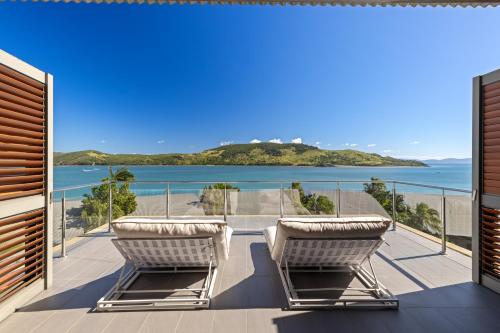 a balcony with two chairs and a view of the ocean at Yacht Club Villas on Hamilton Island by HIHA in Hamilton Island