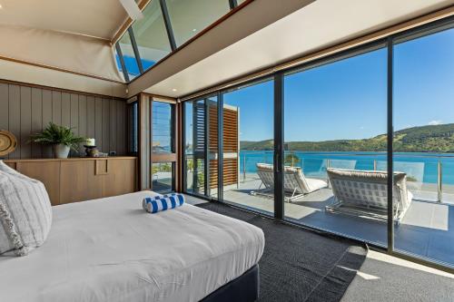 a bedroom with a bed and large glass windows at Yacht Club Villas on Hamilton Island by HIHA in Hamilton Island