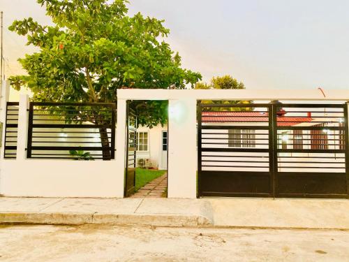 a white and black garage door with a tree at Casa Oueilhe Vacacional , cerca del mar in Tecolutla