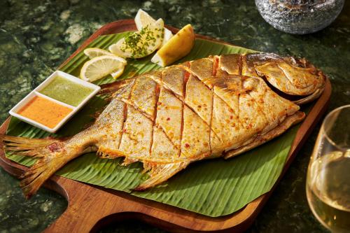 a fish on a green plate on a wooden board at Centara Mirage Resort Mui Ne in Mui Ne