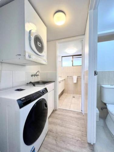 a bathroom with a washer and a sink and a toilet at The Noosa Apartments in Noosa Heads