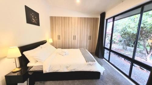 a bedroom with a bed and a large window at Camellia Grove Retreat in Mount Macedon