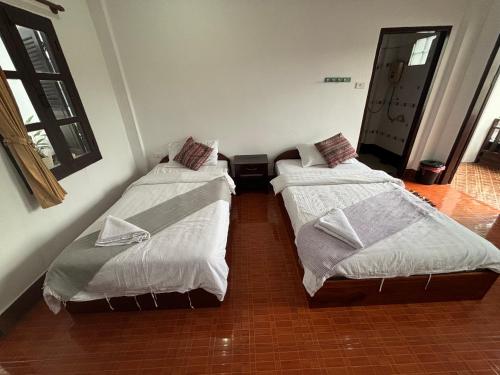 two beds sitting next to each other in a room at Maophasok river side hotel in Luang Prabang