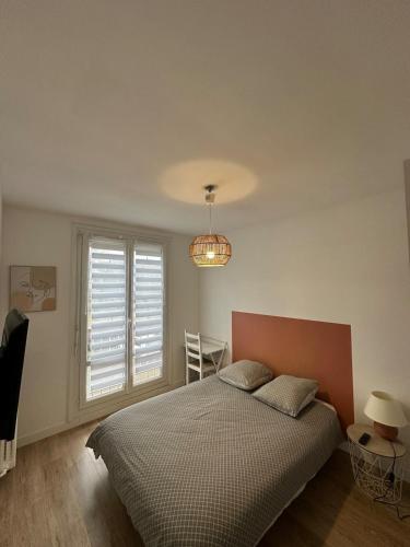 une chambre avec un lit, une fenêtre et un lustre dans l'établissement Pause Déco, à Saint-Brieuc