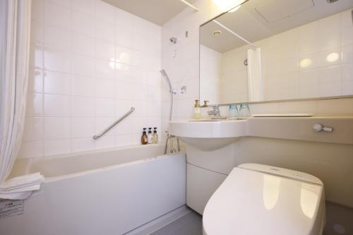 a bathroom with a toilet and a tub and a sink at Hotel the Lutheran in Osaka