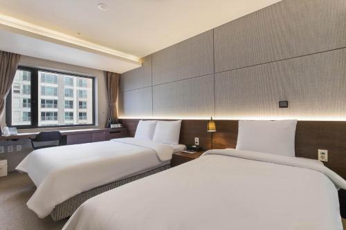 a hotel room with two beds and a window at Hotel Elora in Suwon