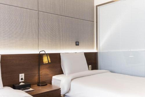 a bedroom with a white bed and a lamp at Hotel Elora in Suwon