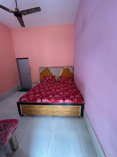 a bedroom with a red bed in a pink wall at Chandrakala Ashram in Naimishāranya
