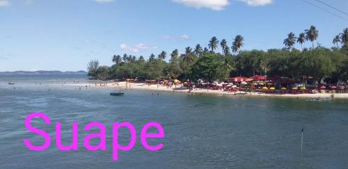 une vue d'une plage avec des gens dans l'eau dans l'établissement Casa temporada Caípe fundo, à São Francisco do Conde