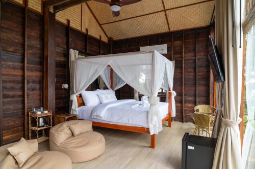 a bedroom with a canopy bed and a chair at RoomQuest THEVA Resort Koh Samui in Koh Samui 