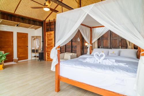 a bedroom with a white bed with a mosquito net at RoomQuest THEVA Resort Koh Samui in Koh Samui 