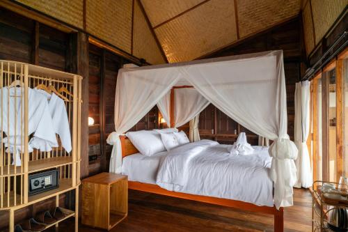 a bedroom with a bed with a canopy at RoomQuest THEVA Resort Koh Samui in Koh Samui 