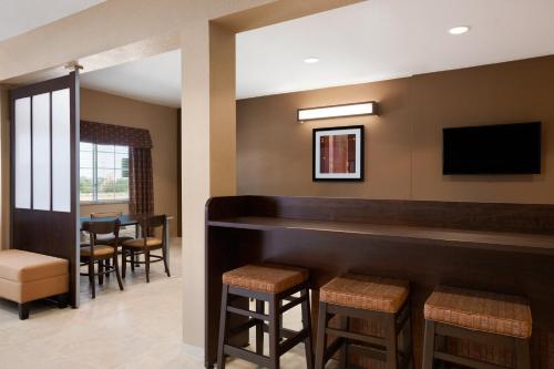 a bar in a restaurant with stools and a tv at Microtel Inn & Suites by Wyndham in Midland
