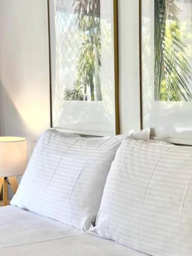 a white bed with white pillows and a window at The Noosa Apartments in Noosa Heads
