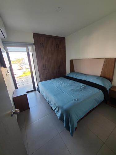a bedroom with a bed with a blue comforter at Depa los robles fracc aldea hortus in Naranjo