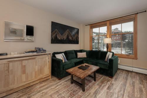 a living room with a green couch and a table at Premium Unit 2216 - 1 Br - Zephyr Mountain Lodge condo in Winter Park