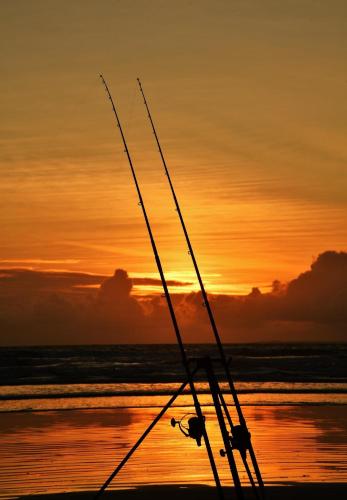 two fishing rods sitting on the beach at sunset at Peaceful bliss 200 meters from the beach in Rossnowlagh