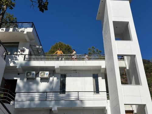 two men standing on a balcony of a building at The Shalam Resort श्रीकृष्ण शरणं मम in Lansdowne