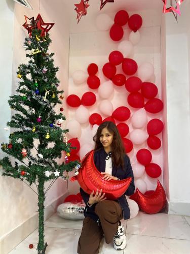 a woman is sitting next to a christmas tree at The Shalam Resort श्रीकृष्ण शरणं मम in Lansdowne