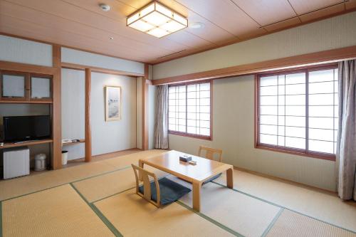 a living room with a table and two windows at HOTEL MYSTAYS Matsuyama in Matsuyama