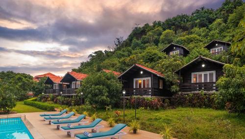 a row of lounge chairs next to a resort at Highland Sarovar Portico Sindhudurg in Bhogwe