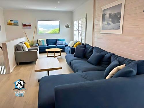 a living room with blue couches and a table at Stones Throw to Beach & Chiton Surf Club in Hayborough