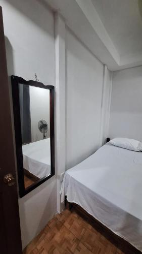 a bedroom with a mirror and a white bed at Casa Palmera in Puerto Jiménez