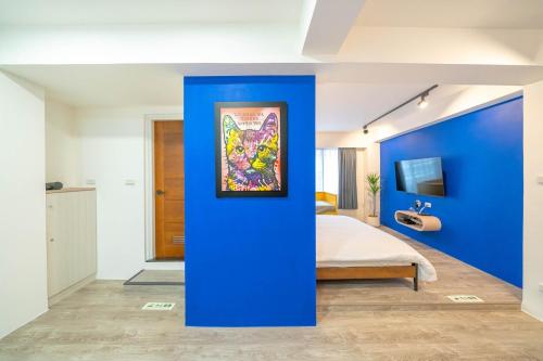 a blue room with a bed and a painting on a blue wall at Tsum chill in Tainan