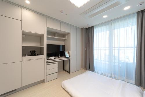 a bedroom with a bed and a desk and a television at Bella Stay in Chuncheon