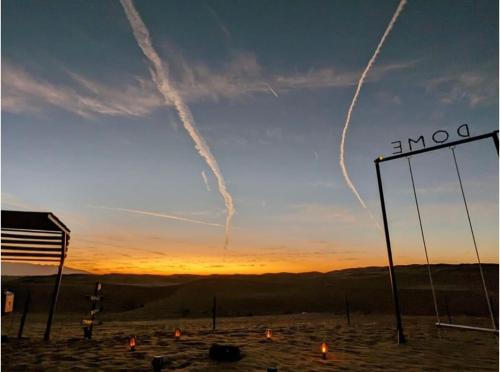two planes are leaving contrails in the sky at sunset at Dome private camp 1 in Al Raka