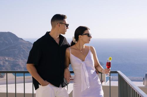 a man and woman standing on a balcony with a drink at Mirthea Suites in Mírthios