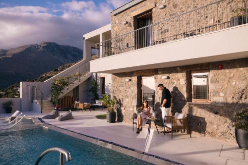 a man and woman sitting on a patio next to a pool at Mirthea Suites in Mírthios