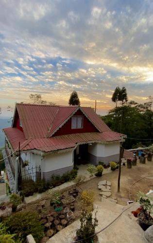 Casa roja y blanca con techo rojo en Máple farmstay, en Darjeeling
