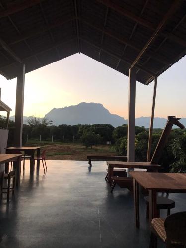 a patio with tables and chairs and a view of a mountain at Daraga ดารกะ in Chiang Dao