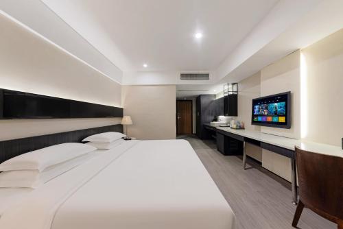 a bedroom with a large white bed and a television at 重庆江北观音桥高悦酒店地铁站店KaoYu Hotel in Chongqing