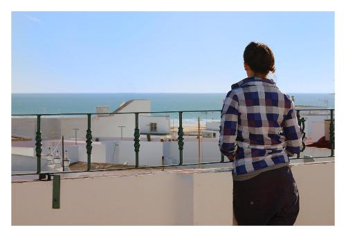 a man standing on a balcony looking at the ocean at Hostal La Posada in Conil de la Frontera