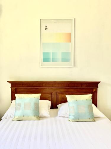 a bed with two pillows and a picture on the wall at Tamarind Hill Country Escape in Digana