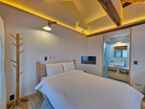 a bedroom with a large white bed and a bathroom at Hanokstay mokhwa in Gyeongju