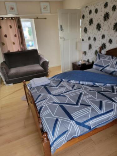 a bedroom with a bed with a blue comforter and a couch at Abakwa Red in Kingsthorpe